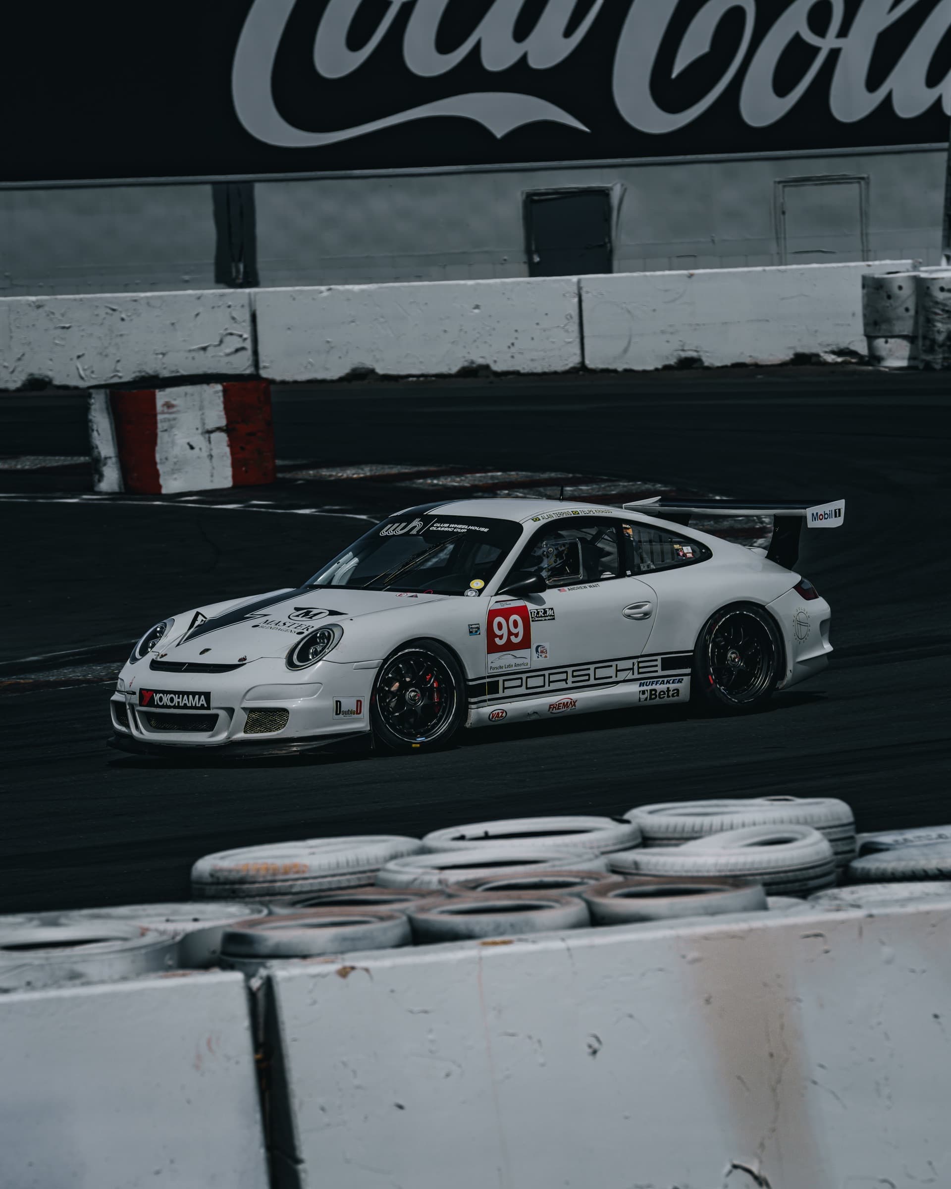 White #99 Porsche 911 GT3 Cup on track before the Coca-Cola wall