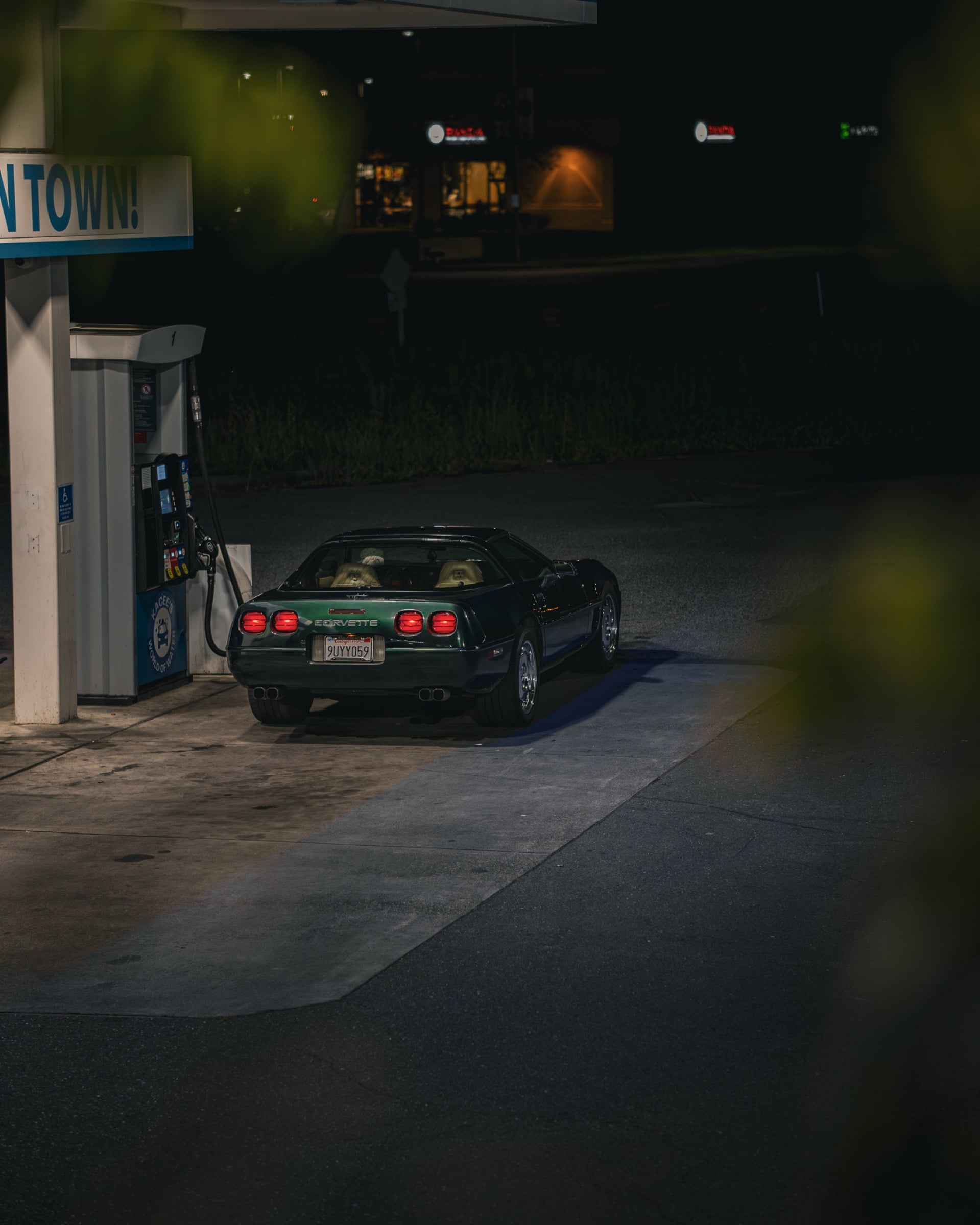 Green Corvette C4 at a gas station at night